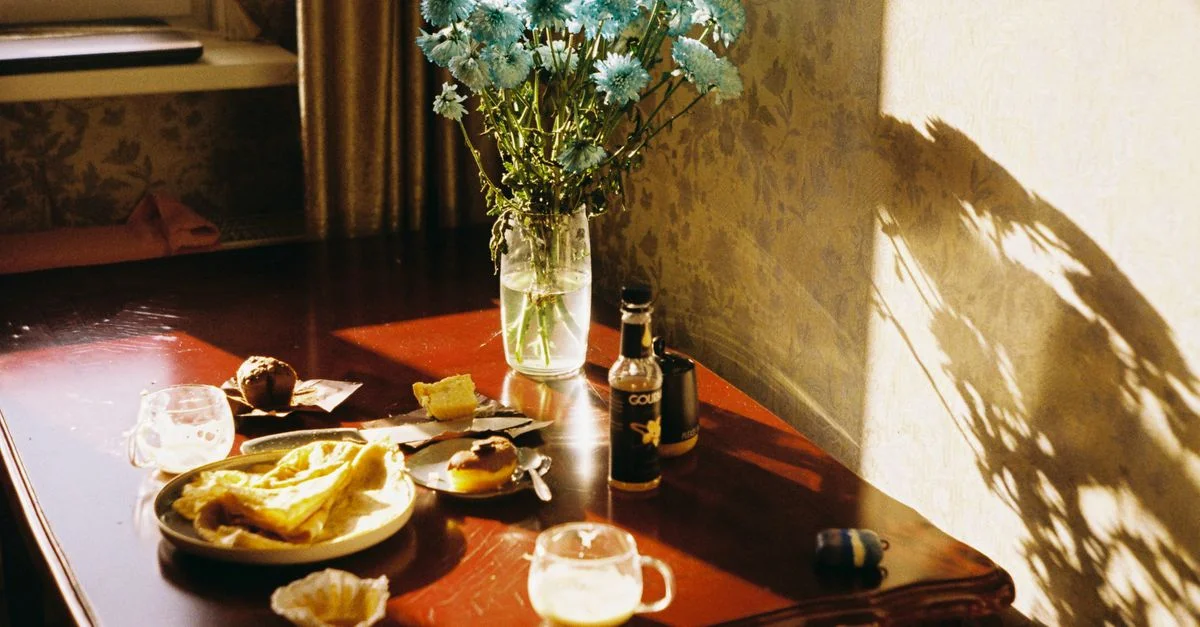 Une scène de cuisine lumineuse et accueillante avec le petit-déjeuner et un vase de fleurs à la lumière naturelle.